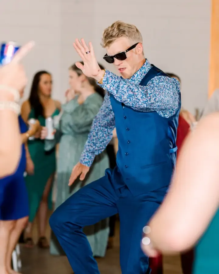 A guest in sunglasses and a vest busting a move on the dance floor